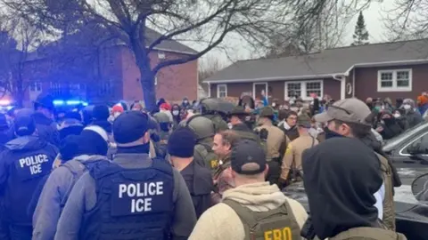 Masked ice agents and protestors in front of a home on Dorset Street, South Burlington.